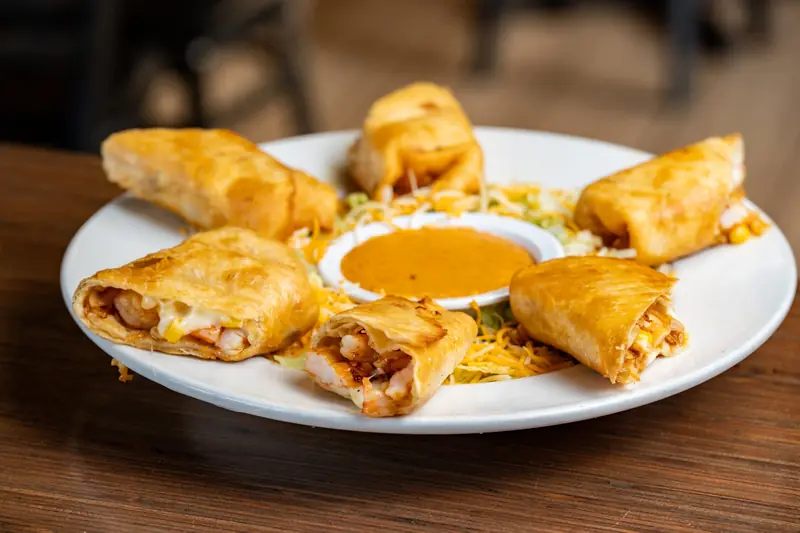 Golden fried bites around a cup of queso
