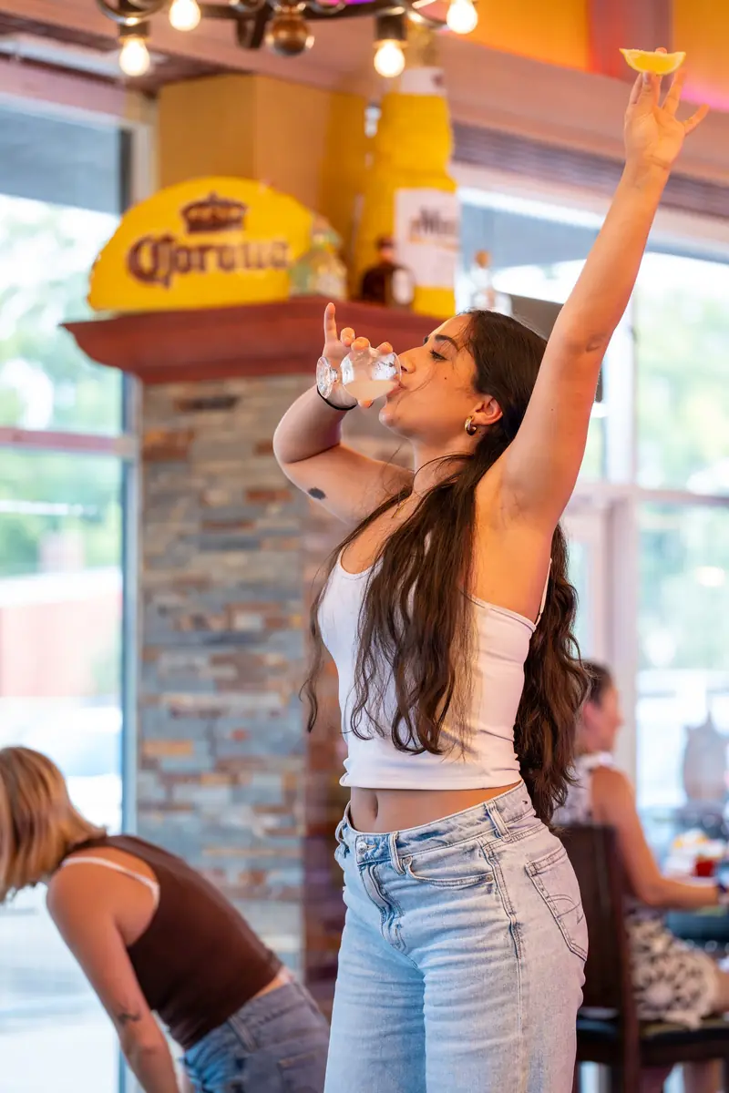 Woman cheering under a Corona sign